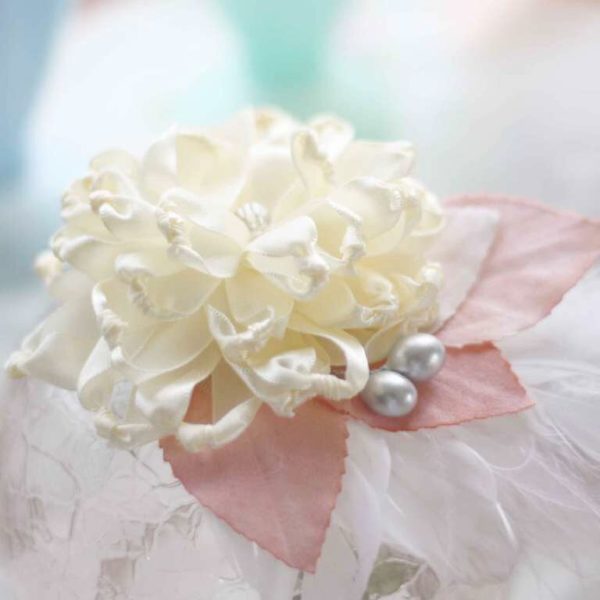 A Fabric Flower Fascinator with peach millinery leaves and a feather