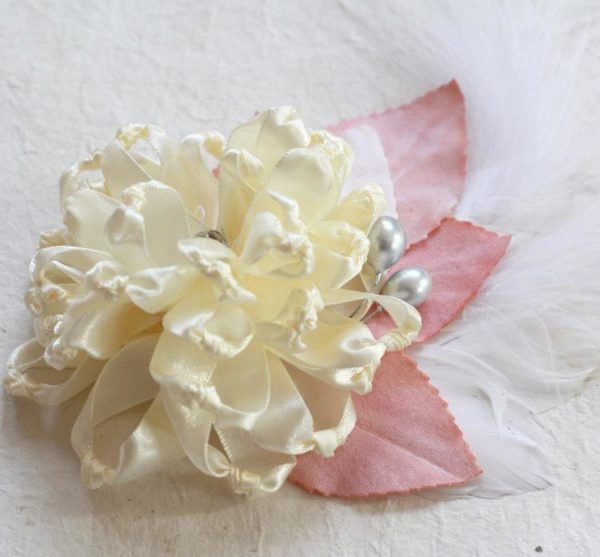 A Fabric Flower Fascinator with peach millinery leaves and a feather